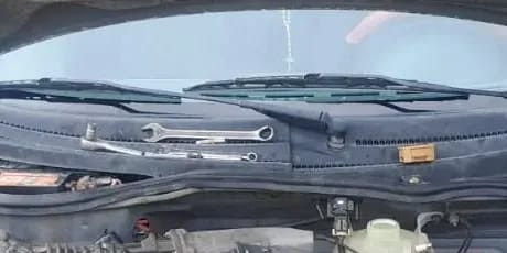 Llaves de trabajo apoyadas bajo el parabrisas de un auto en el taller.