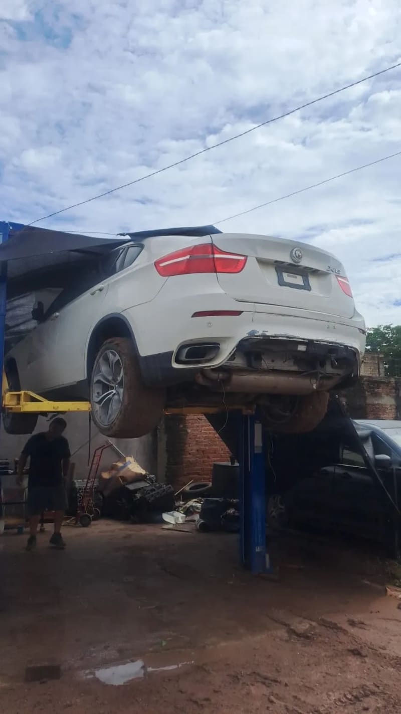 Foto real del taller: camioneta BMW X6 levantada en el elevador para revisión.